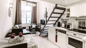 A modern kitchen with a built-in oven, a dining area with a table and chairs, and a staircase leading to an upper level. - Andrassy 1 Apartment (Budapest)