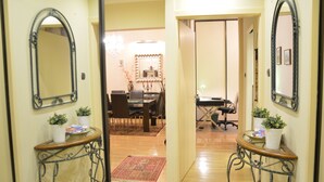 A hallway with a dining area, two potted plants, a mirror, and a chandelier. - Bajcsy 1 Apartment (Budapest)