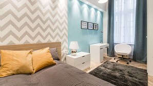 Un dormitorio moderno con cama, mesitas de noche, escritorio y una silla.