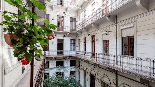 Un edificio de varios pisos con balcones, ventanas grandes y plantas colgantes.