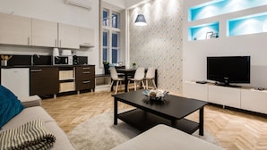 Un apartamento moderno con cocina, comedor y sala de estar. Cuenta con un sofá, una mesa de comedor, un televisor y una cafetera.