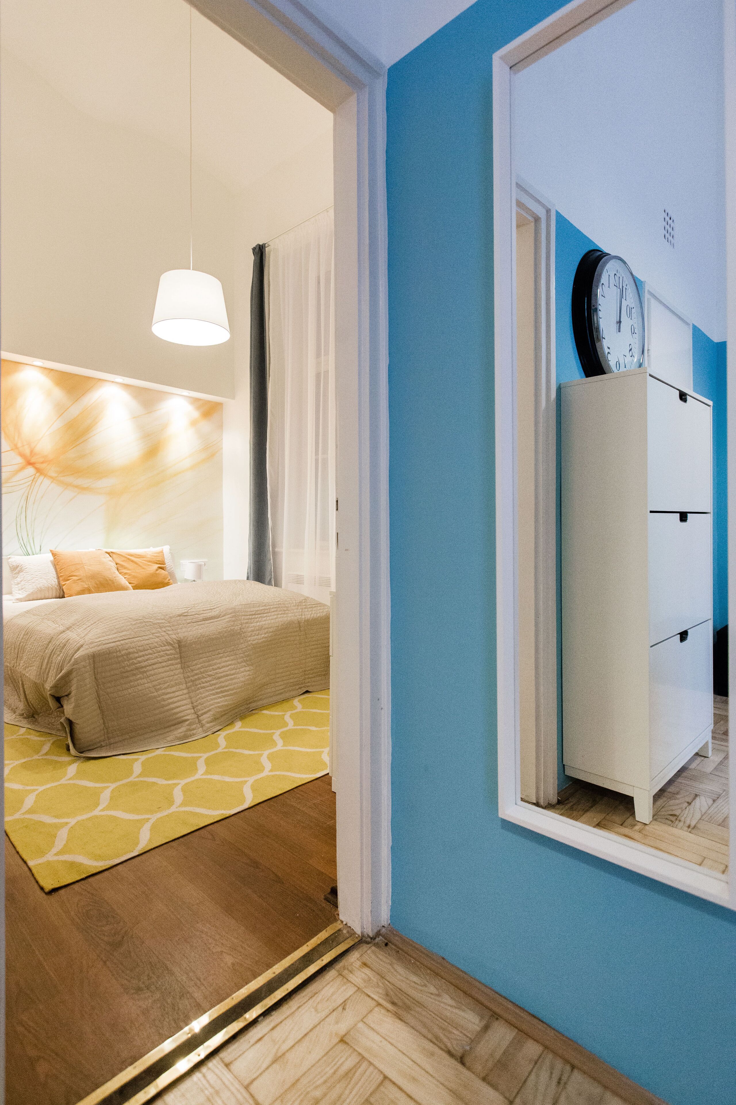 Un dormitorio con una cama, una mesita de noche, una lámpara y un reloj de pared.