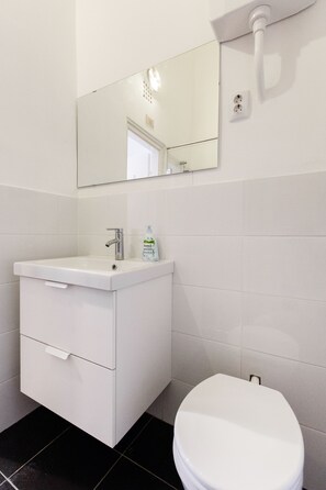 A bathroom with a white sink, mirror, and toilet.