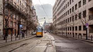 A tram on a city street with buildings on either side. - Balassi 27 Apartment (Budapest)