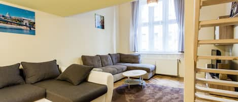 A modern living room with a sectional sofa, a round coffee table, and a wooden staircase.