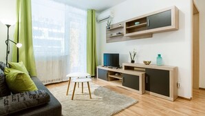 Una sala de estar moderna con sofá, televisión y estanterías de madera.