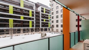 Un edificio residencial de varios pisos con balcones, suelo cubierto de nieve y vistas de edificios vecinos.