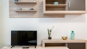 Una sala de estar moderna con un televisor de pantalla plana, estanterías de madera y un armario.