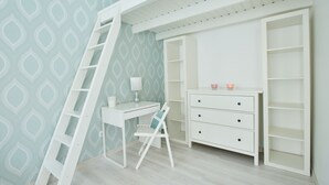 A room with a white desk, a chair, a ladder, and a shelving unit. - Dob 11 Apartment I. (Budapest)