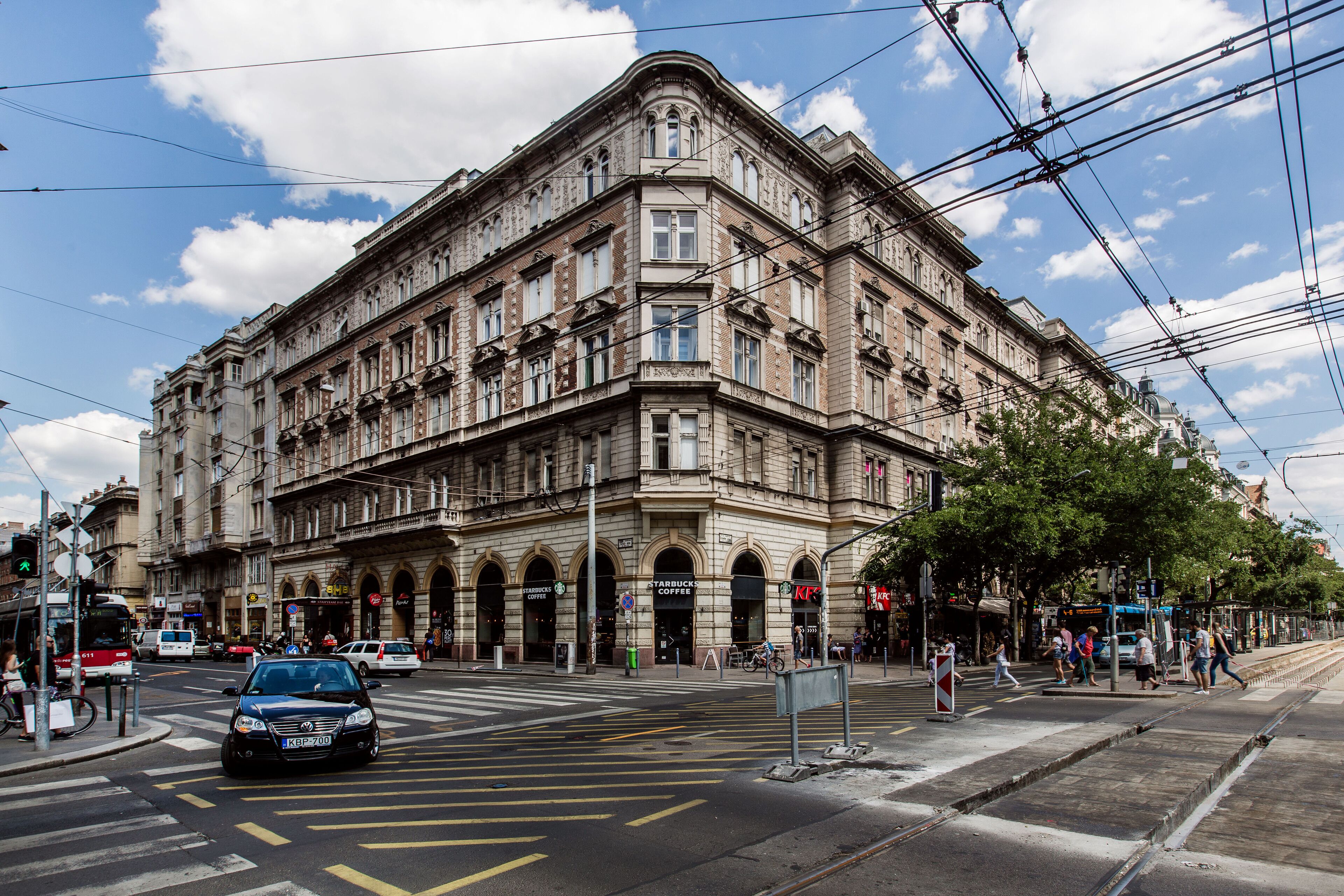 Ein historisches Gebäude mit mehreren Stockwerken, großen Fenstern und einem Hauseingang an der Ecke.