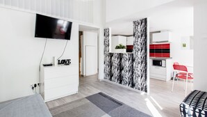 Uma sala de estar moderna com televisão de tela plana, um rack branco e um sofá cinza.
