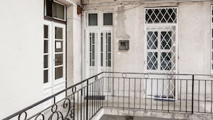 A balcony with a metal railing, a white door, and a window with a grid pattern.