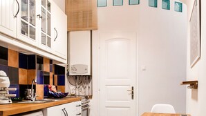 A compact kitchen with a washing machine, a sink, and a wooden table with a chair.