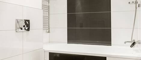 A modern bathroom with a white toilet, a black-tiled shower area, and a white sink.