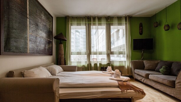 Ein Hotelzimmer mit zwei Betten, einem Sofa, einem Fernseher und einem großen Gemälde an der Wand.