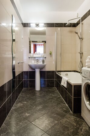 A modern bathroom with a sink, mirror, shower, and washing machine. - Hollo 12 Apartment II. (Budapest)