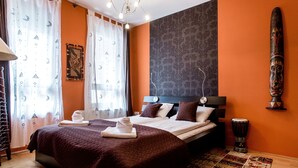 Ein Hotelzimmer mit einem großen Bett, einem Kopfteil, einem Beistuhl und einem dekorativen Wandbild.