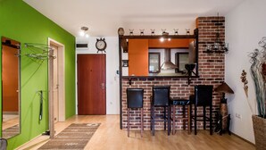 Eine Küche mit Backsteinwand, einer Holzauslage und drei schwarzen Barhocker.