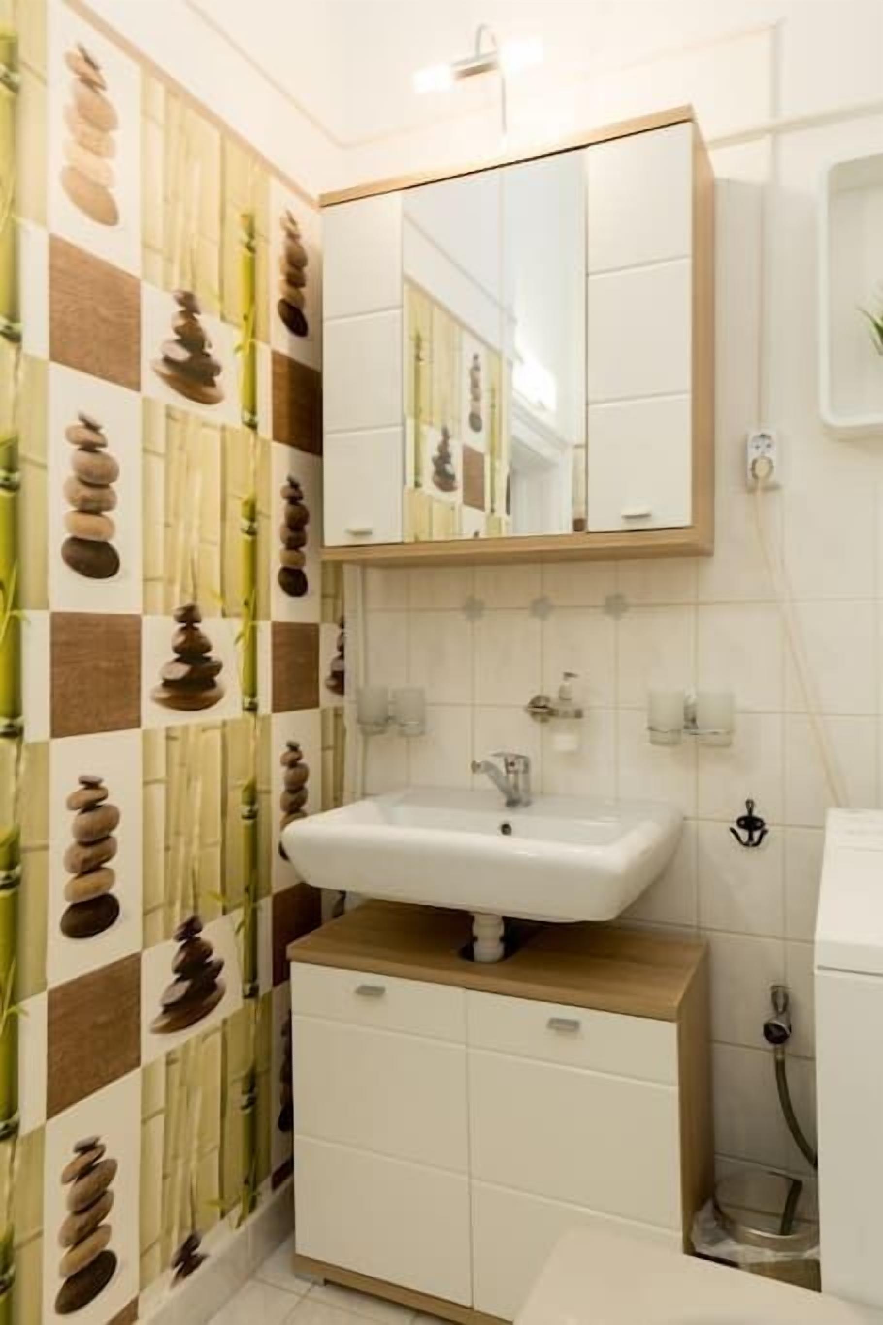 Un baño con lavamanos, espejo y armario.