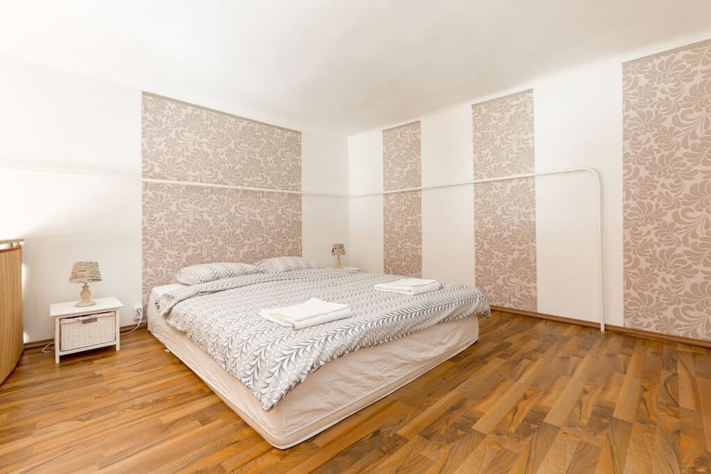 Un dormitorio con cama, mesitas de noche y papel tapiz estampado.