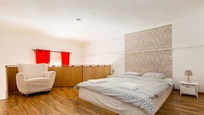 A bedroom with a large bed, a chair, a desk, and a nightstand. - Hunyadi 3 Apartment (Budapest)