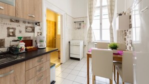 A modern kitchen with wooden cabinets, a coffee machine, and a dining area with a table and chairs. - Hunyadi 3 Apartment (Budapest)