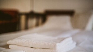 Una cama bien tendida con sábanas blancas y cabecera de madera.
