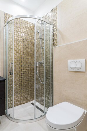 A modern bathroom with a glass-enclosed shower, a white toilet, and a wall-mounted light switch. - Kazinczy 11 Apartment (Budapest)