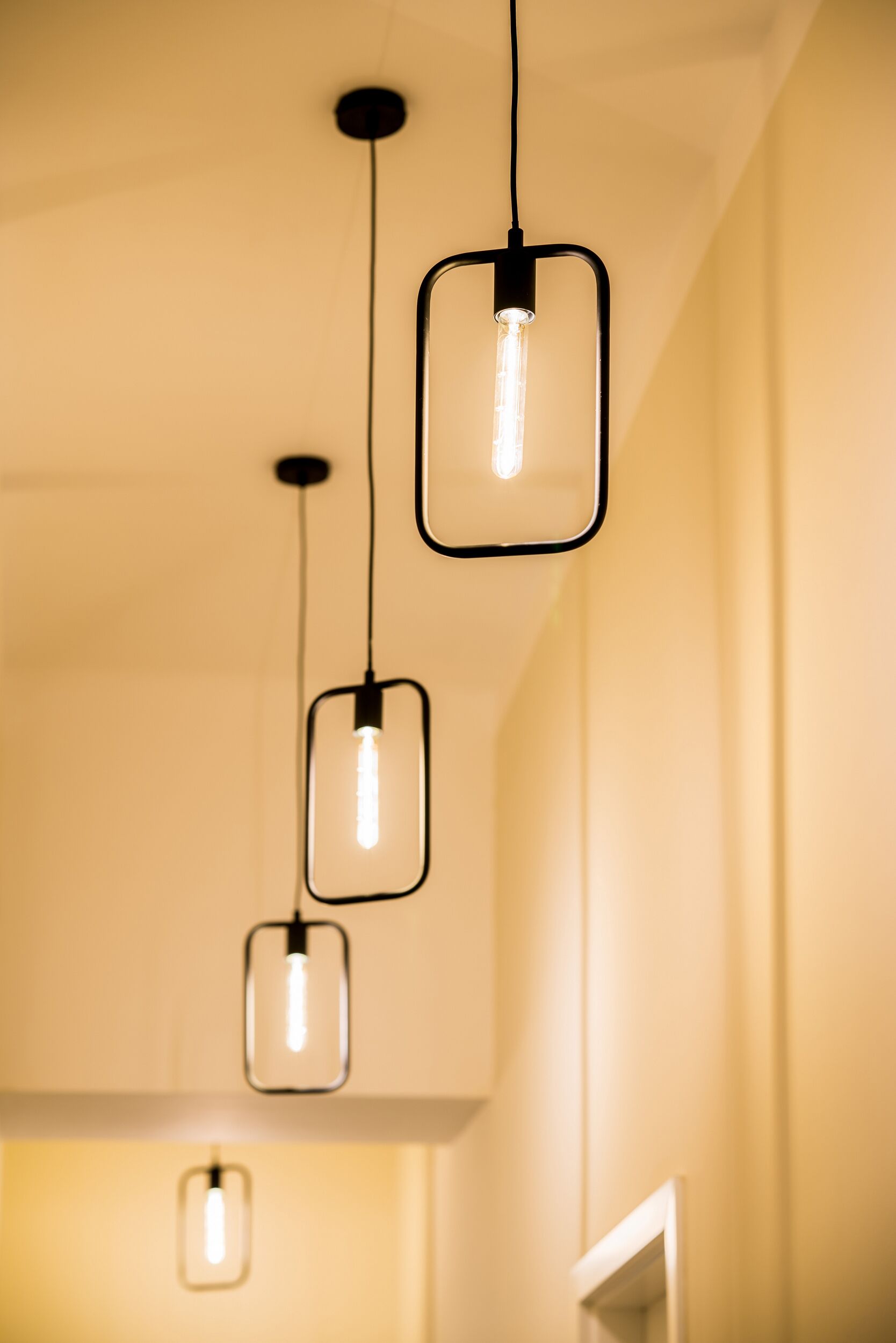 Three pendant lights hanging from the ceiling in a room with plain walls.
