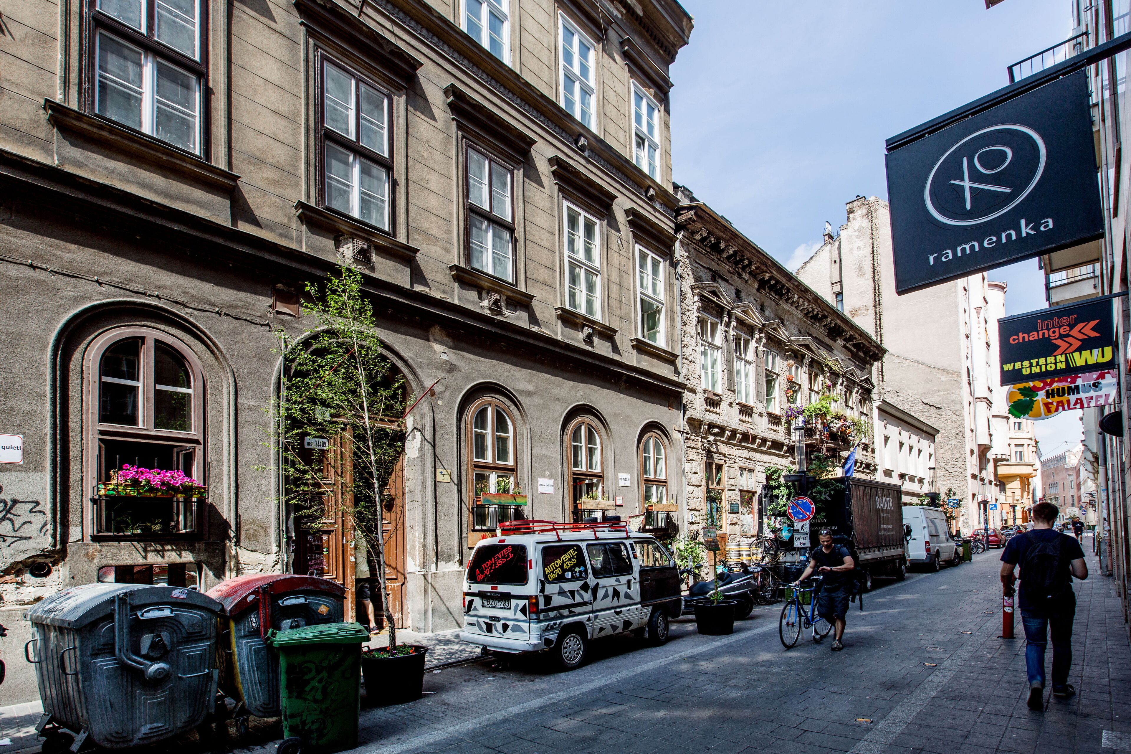 A street with a building featuring large windows and a sign for 'ramenka'.
