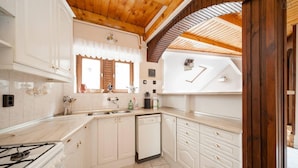 A kitchen with white cabinets, a dishwasher, and a stove. - Kecskemeti 11 Apartment (Budapest)
