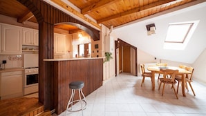 A kitchen with wooden beams, a dining area with a table and chairs, and a small window. - Kecskemeti 11 Apartment (Budapest)