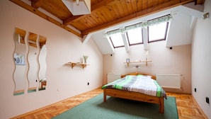 A bedroom with a wooden ceiling, a bed with a green and white striped bedspread, wooden flooring, and a skylight with a green curtain. - Kecskemeti 11 Apartment (Budapest)