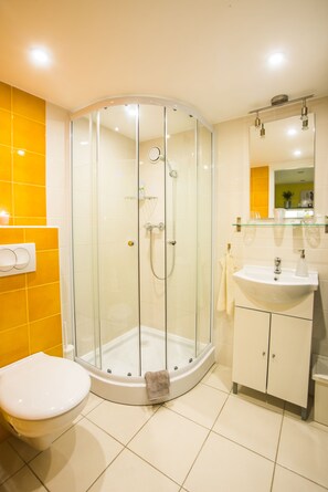 A modern bathroom with a glass-enclosed shower, a white sink, and a toilet.