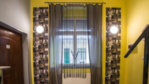 Ein Zimmer mit Fenster, Vorhängen, Heizkörper und Wand mit geometrischem Muster.
