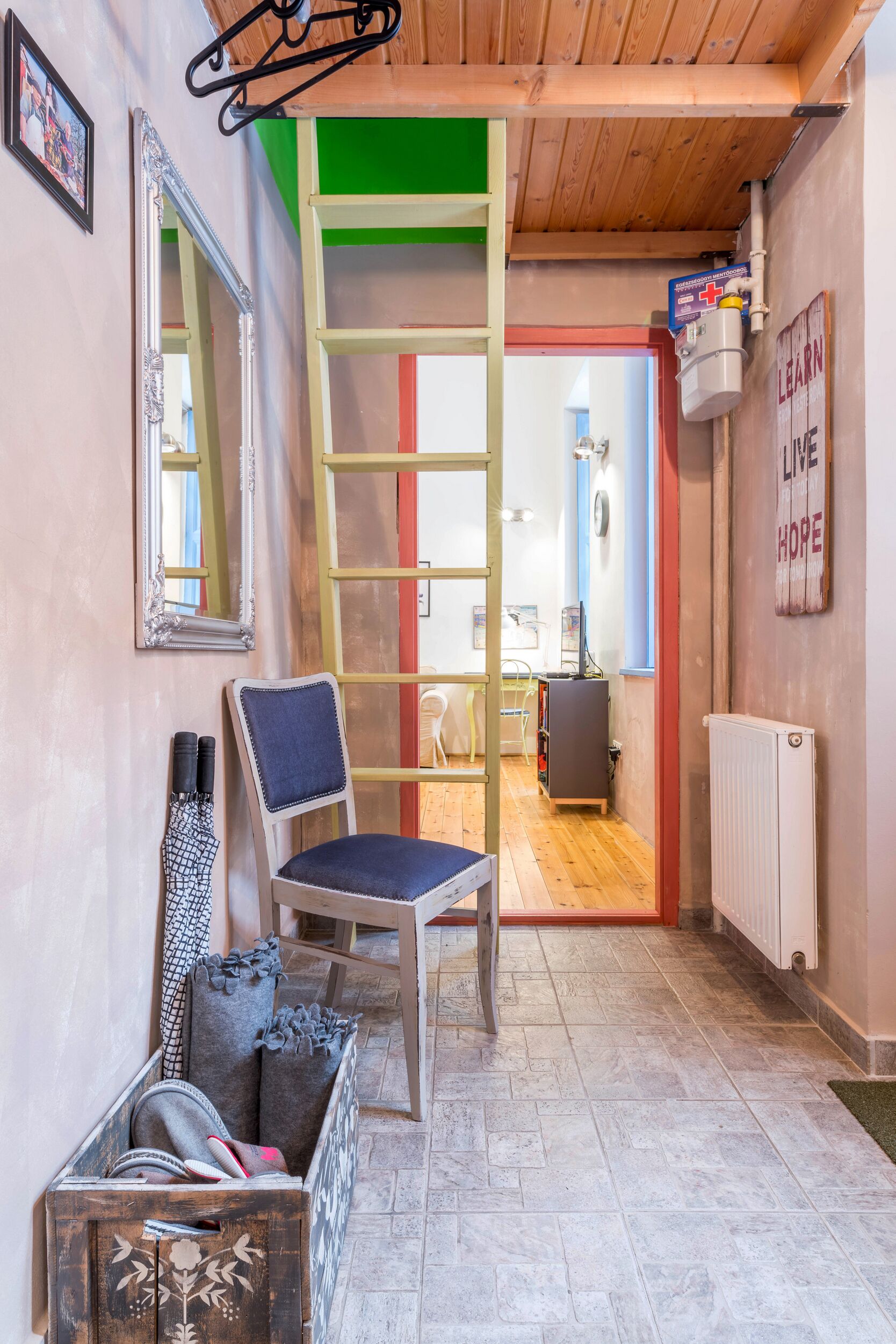 A narrow hallway with a wooden chair, a ladder, and a radiator.