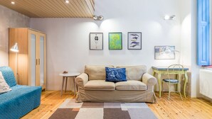 A cozy living room with a sofa, a small table, and a cabinet. There are three framed pictures on the wall. - Kiraly 99 Apartment (Budapest)