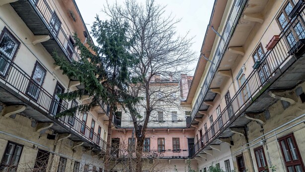 A courtyard with a central tree surrounded by multi-story buildings with balconies. - Kiraly 99 Apartment (Budapest)
