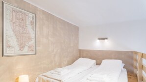 A neatly made twin bed with white linens, a wall-mounted map, and a bedside table with a lamp. - Kiraly 99 Apartment (Budapest)