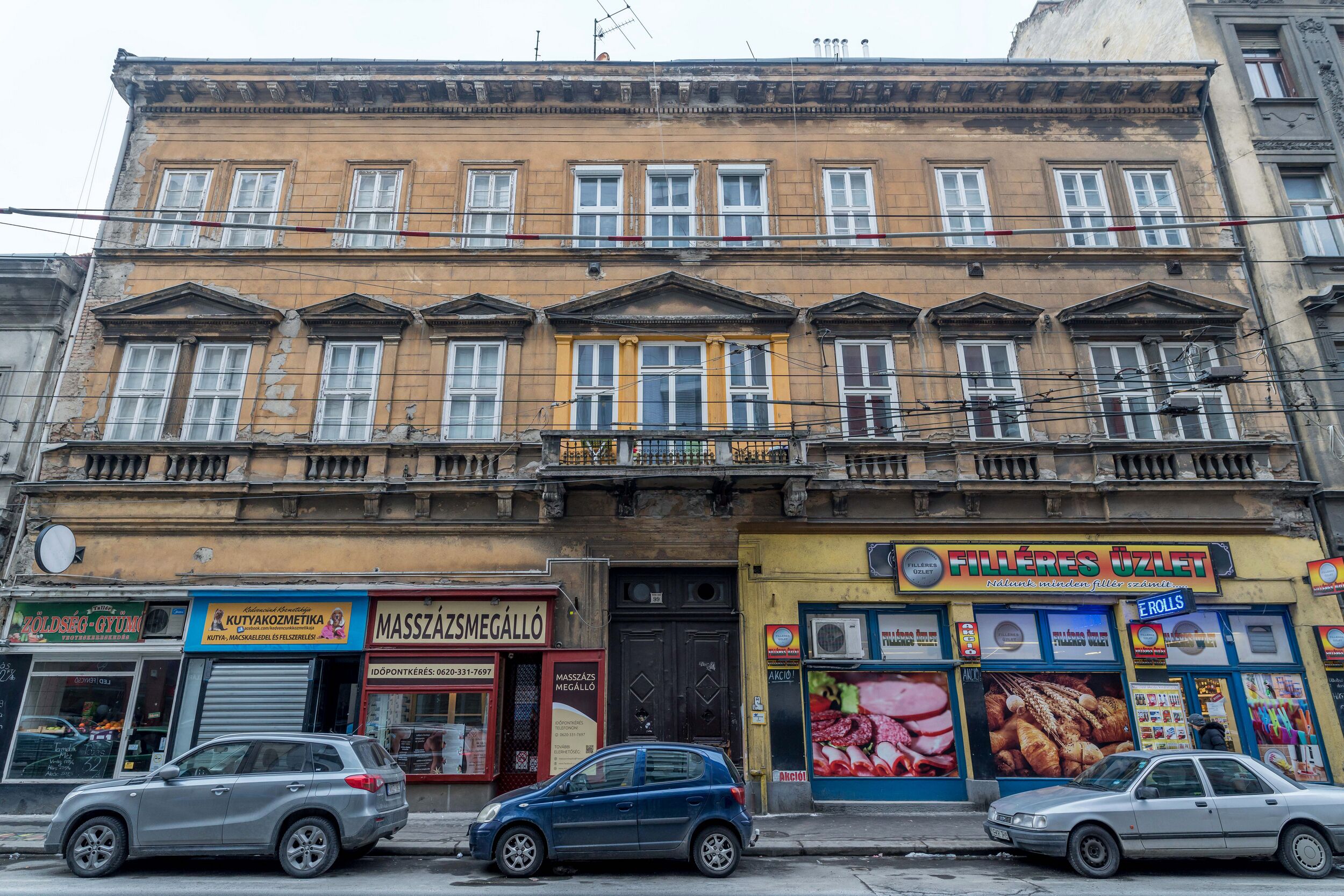 A multi-story building with various shops on the ground floor, including a bakery and a massage parlor.