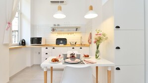 Une cuisine moderne avec des meubles blancs, une table à manger avec des chaises et un vase de fleurs posé sur la table.