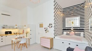 Un espace de vie moderne et compact comprenant un coin cuisine, un coin repas et une chambre avec un grand lit et une table de chevet.