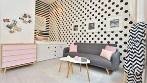 Un salon moderne avec un canapé gris, une table basse blanche et une commode rose.