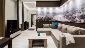 A modern living room with a sectional sofa, a flat-screen TV, and a large cityscape mural on the wall. - Klauzal 10 Apartment (Budapest)