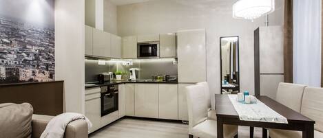 A modern kitchen with white cabinets, a microwave, and a dining area with a table and chairs.