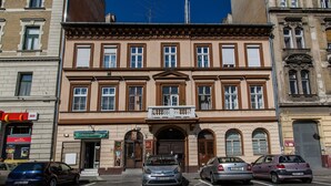 A multi-story building with a central entrance, several windows, and a parking lot with cars. - Klauzal 10 Apartment (Budapest)