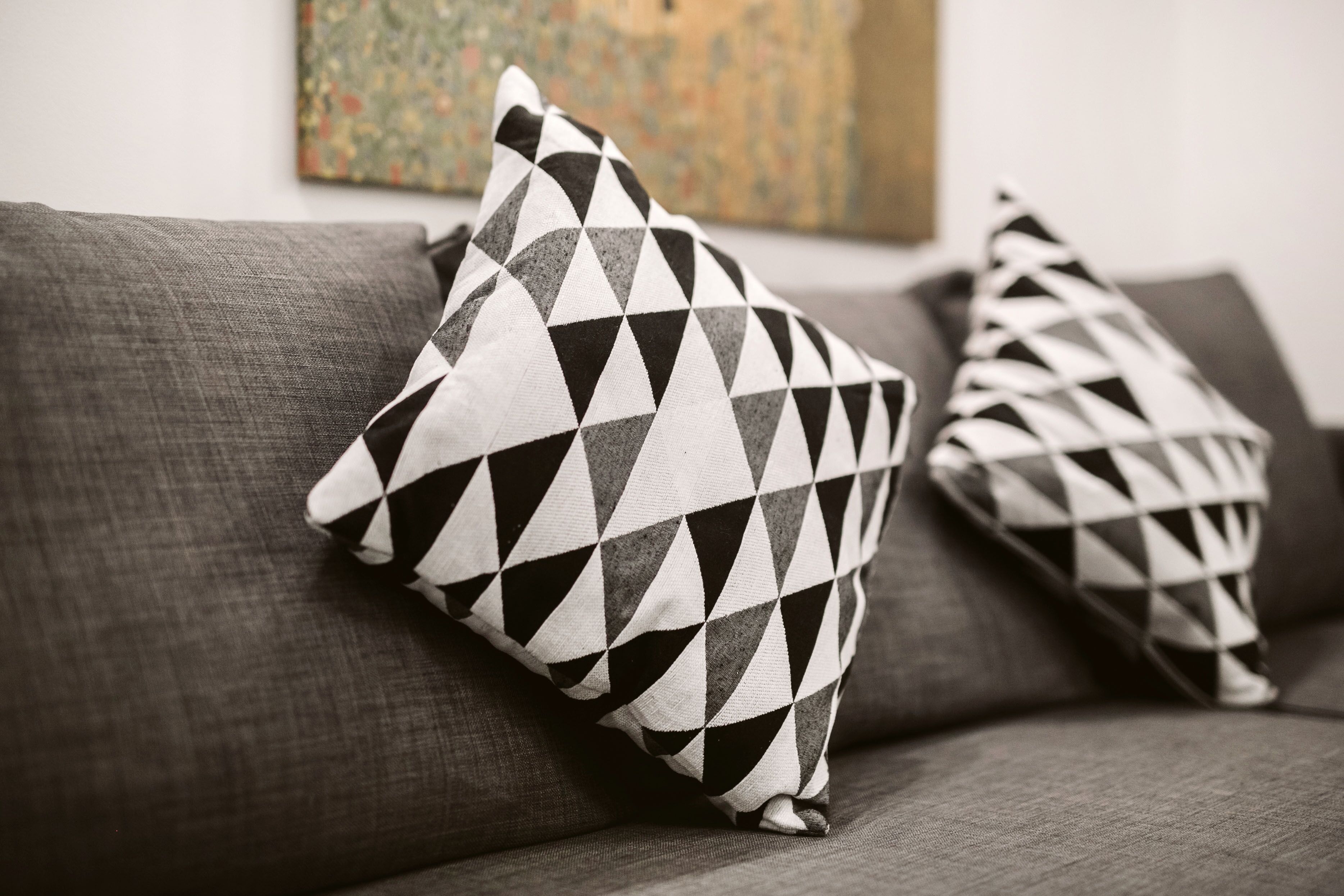 A gray sofa with two patterned pillows.