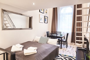 A hotel room with a bed, a desk, a chair, a mirror, and a window with curtains.