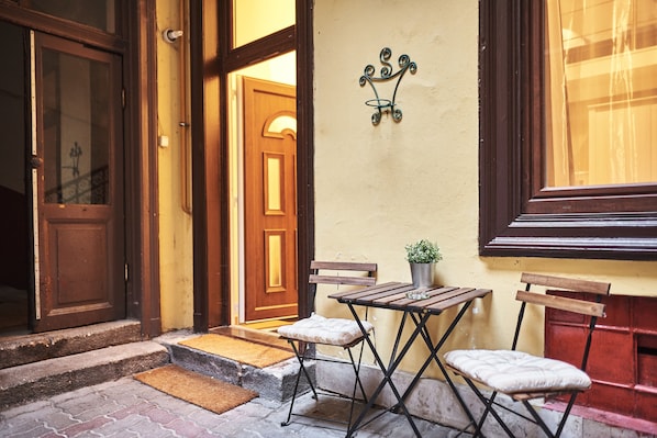 A wooden door, a bench, a small table with a potted plant, and a wall-mounted light fixture.
