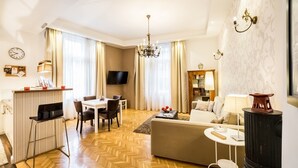 A modern living room with a sofa, a dining table with chairs, a TV, and a fireplace. - Magas 5 Apartment (Budapest)